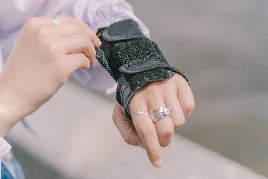 A person fastening the strap of a black wrist brace