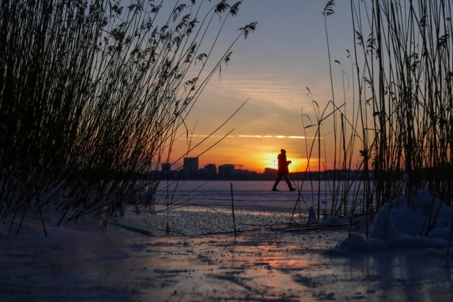 A person walking alone on a snowy path at sunset